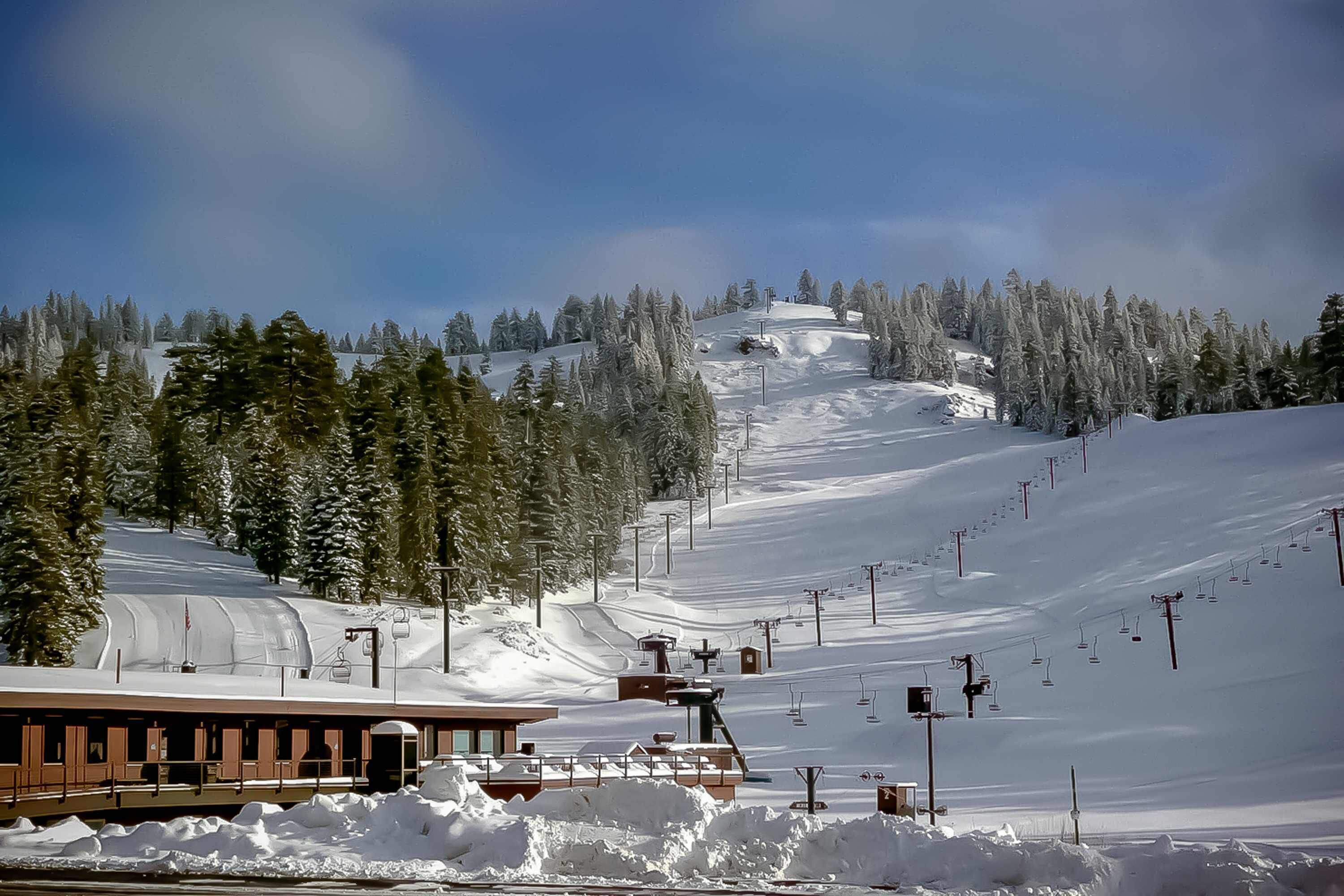 A snow-covered ski slope with a building and ski lift infrastructure.