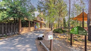 Ett skogsområde med en byggnad som är märkt med skylten ”Pozi Building” och en skylt som visar vägen till entrén till naturcentret.