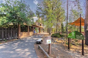A forested area with a building labeled 'Pozi Building' and a sign pointing to the 'nature center entrance.' - Lovely and spacious family-friendly home with SHARC passes & private hot tub (Sunriver)