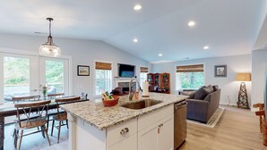 A modern kitchen with a granite countertop, white cabinetry, and a built-in dishwasher. - Brand-new home with hot tub, deck, fast WiFi, central AC, & great location (Manzanita)