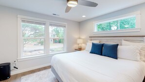 A bedroom with a bed, a ceiling fan, a window, and a lamp. - Brand-new home with hot tub, deck, fast WiFi, central AC, & great location (Manzanita)