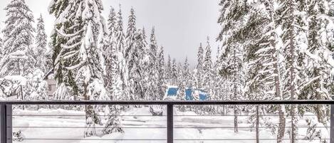 A snowy forest scene with a vehicle in the distance.