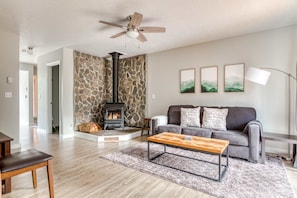 A living room with a stone wall, fireplace, sofa, coffee table, and a ceiling fan.