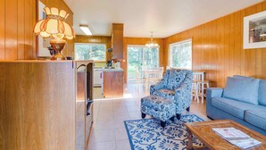 Una habitación con paneles de madera, un sofá, un sillón y una mesita de centro.