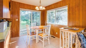 Una habitación con paneles de madera, una mesa de comedor, sillas, una mesita con una bandeja y un banco.