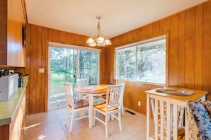 A wooden-paneled room with a dining table, chairs, a small table with a tray, and a bench.