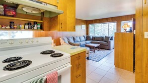 Una cocina con estufa blanca, armarios de madera y un comedor con sofá y mesa.