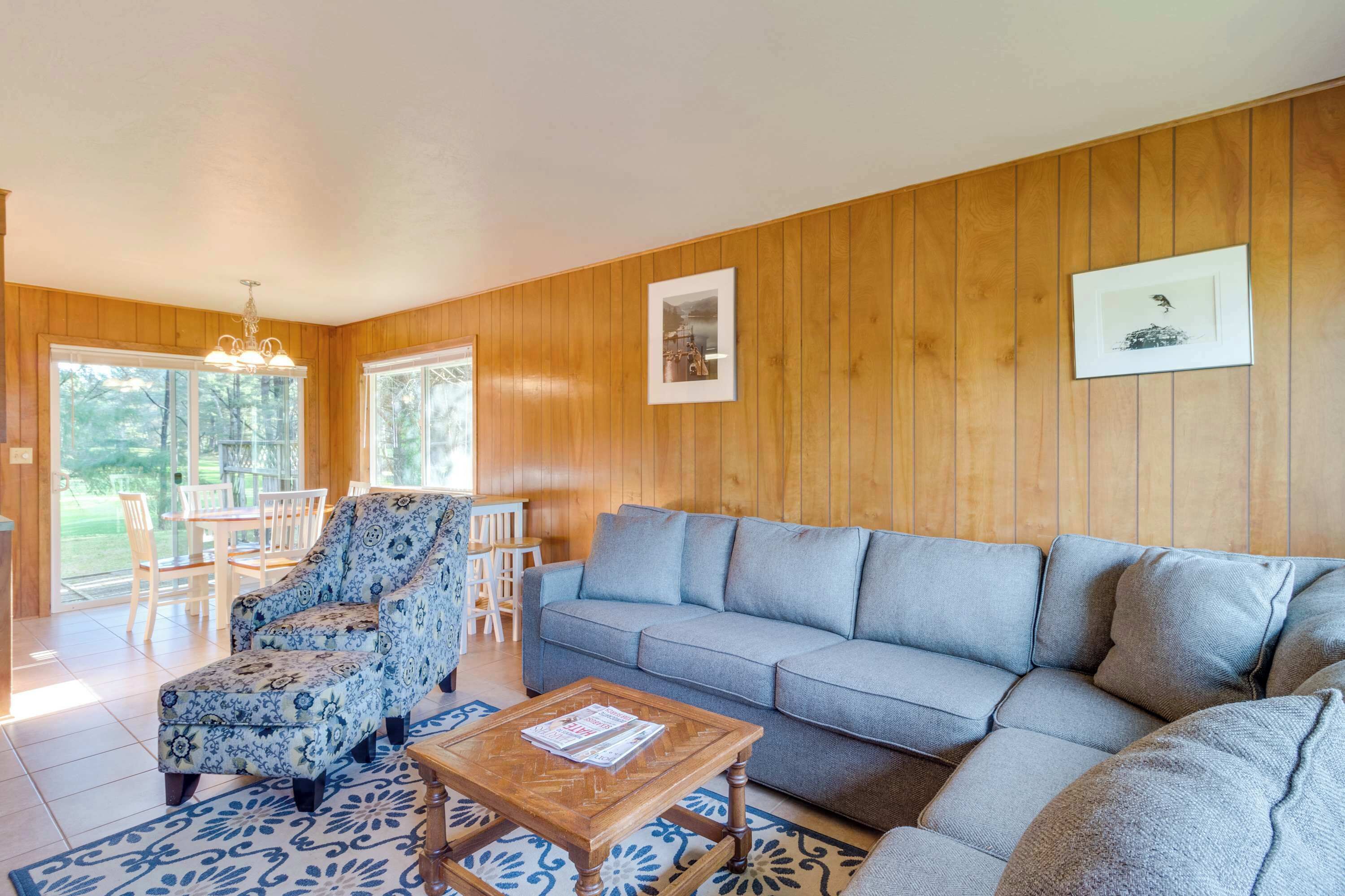 Un salon comprenant un canapé, un fauteuil, une table basse et un coin repas avec des chaises et une table.
