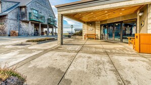 A building with a covered outdoor seating area, a clock, and a storefront with mannequins. - Single-level, dog-friendly home w/ private fenced-in yard & easy beach access (Bandon)