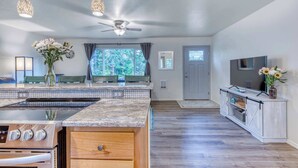A modern kitchen with an island, built-in oven, and a large TV. - Single-level, dog-friendly home w/ private fenced-in yard & easy beach access (Bandon)