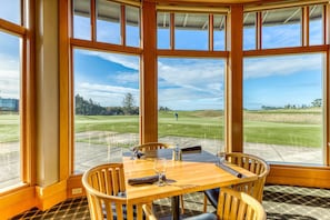 A corner room with large windows, a wooden table, and chairs. - Single-level, dog-friendly home w/ private fenced-in yard & easy beach access (Bandon)