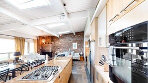 Una cocina moderna con una isla grande, electrodomésticos integrados y una pared decorativa de ladrillo.