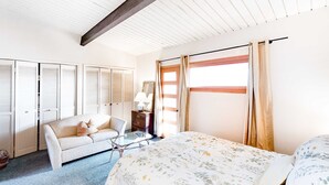 Una habitación con cama, una silla, una mesita y un armario.