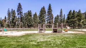 A playground with swings, a slide, and climbing structures. - Unique & secluded forest home with pool, hot tubs, tennis, sauna, & basketball (Black Butte Ranch)