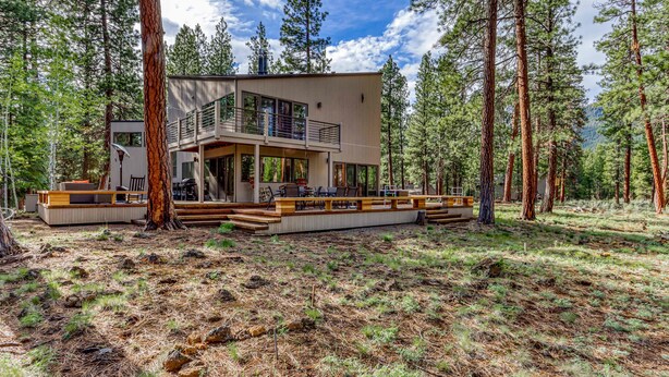 A modern two-story house surrounded by tall pine trees. - Unique & secluded forest home with pool, hot tubs, tennis, sauna, & basketball (Black Butte Ranch)