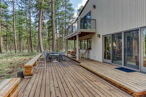 Et moderne hus med træterrasse, spiseplads og stor glasdør.