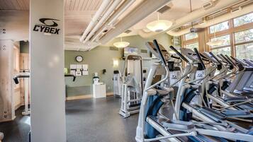 A gym with exercise equipment, a clock, and a bulletin board.