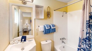 A bathroom with a sink, mirror, towel rack, toilet, and shower. - Retro getaway near beach with fast WiFI - walk to downtown shops & eateries (Bandon)