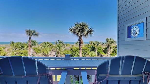 Un patio con vista sull'oceano, palme e un edificio con una finestra circolare.