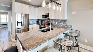 Una cucina moderna con isola centrale, elettrodomestici in acciaio inossidabile e illuminazione a sospensione.