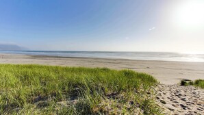 A beach with sand, grass, and a clear sky. - Oceanfront getaway close to Gearhart Golf Links , no pets (Gearhart)