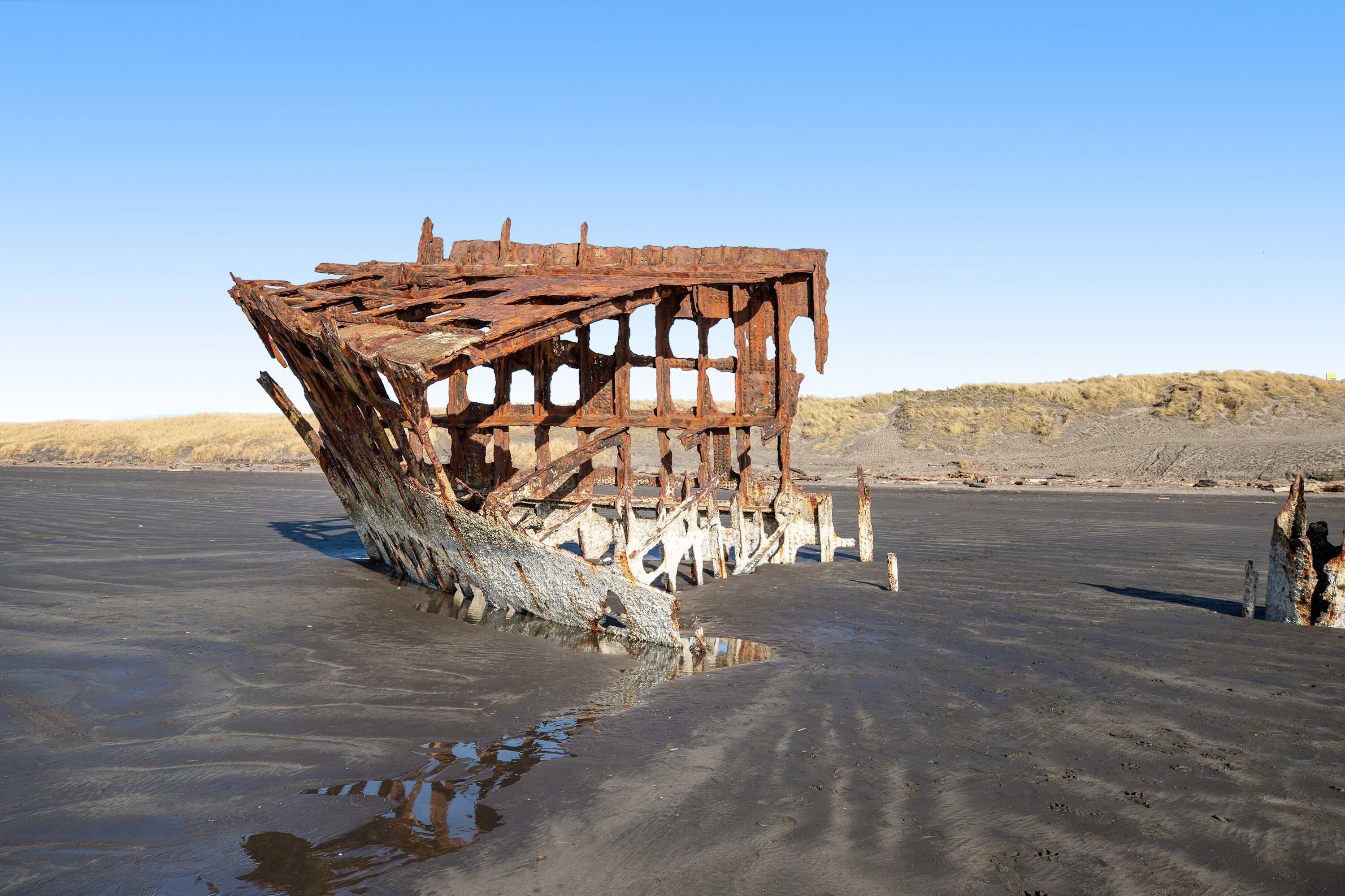 Une grande épave rouillée, échouée sur une plage de sable.