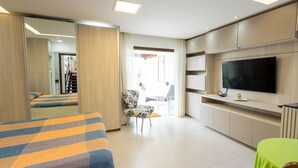 A hotel room with a bed, a chair, a TV, and a green table. - Studio Beira-mar com Vista no Jardim Atl Ntico (Ilhéus)