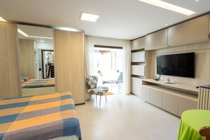 A hotel room with a bed, a chair, a TV, and a green table. - Studio Beira-mar com Vista no Jardim Atl Ntico (Ilhéus)