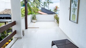 A clean, modern balcony with a bench, potted plants, and a view of palm trees and a building. - Studio Beira-mar com Vista no Jardim Atl Ntico (Ilhéus)
