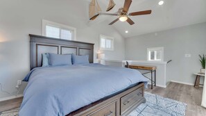Une chambre avec un lit, un bureau, un ventilateur de plafond et une fenêtre.