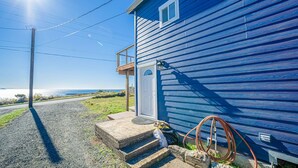 Ett blått hus med en veranda, trappsteg som leder upp till dörren och en slang som hänger på sidan.