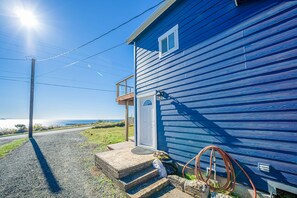 A blue house with a porch, steps leading to the door, and a hose on the side. - Newly Remodeled Ocean View Retreat, Balcony and BBQ (Port Orford)