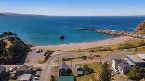 A coastal area with a beach, a pier, and a parking lot with RVs. - Newly Remodeled Ocean View Retreat, Balcony and BBQ (Port Orford)