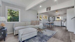 Un salon moderne avec un canapé, un pouf et une table basse en verre.