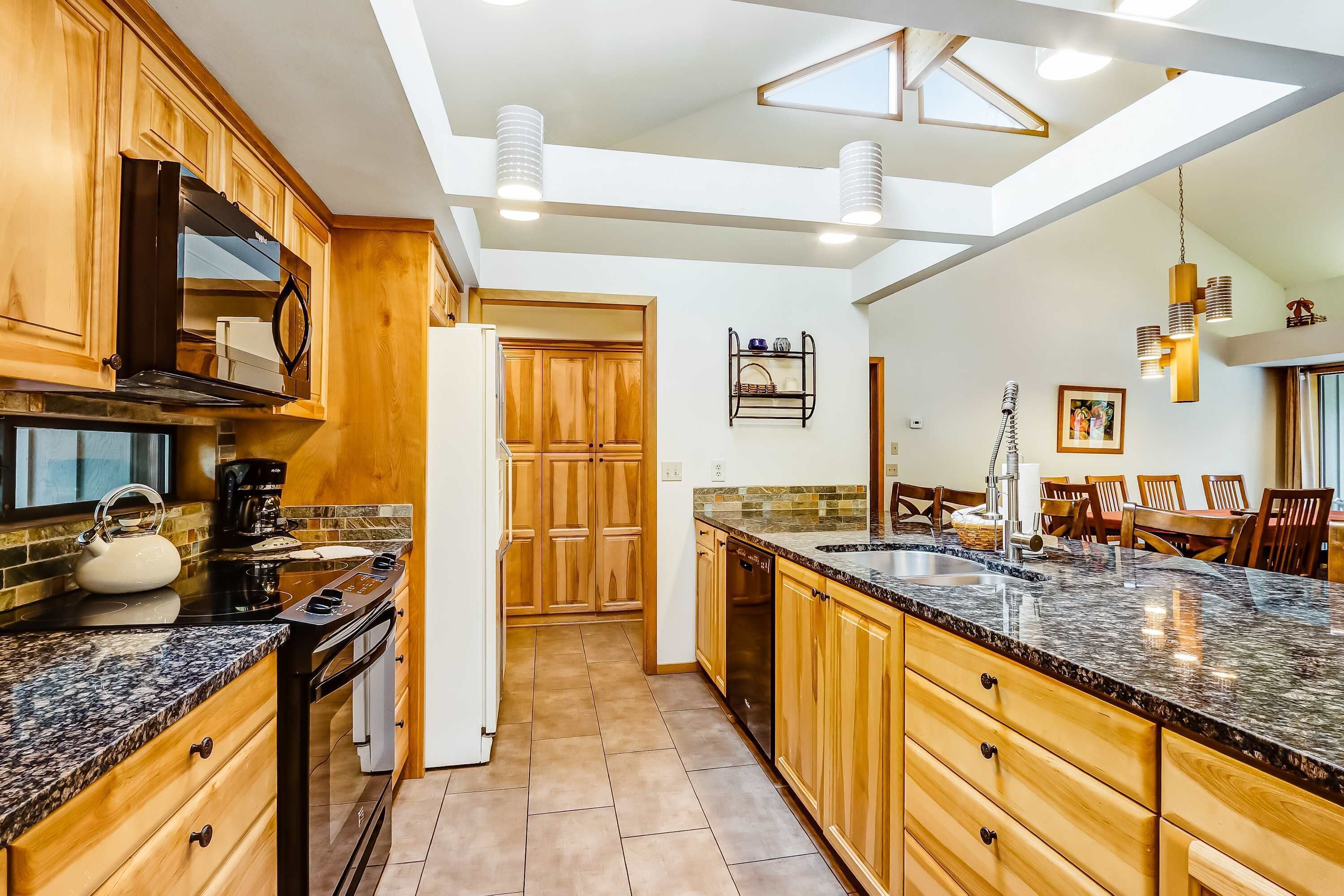 A kitchen with wooden cabinets, a granite countertop, a built-in oven, and a dishwasher.