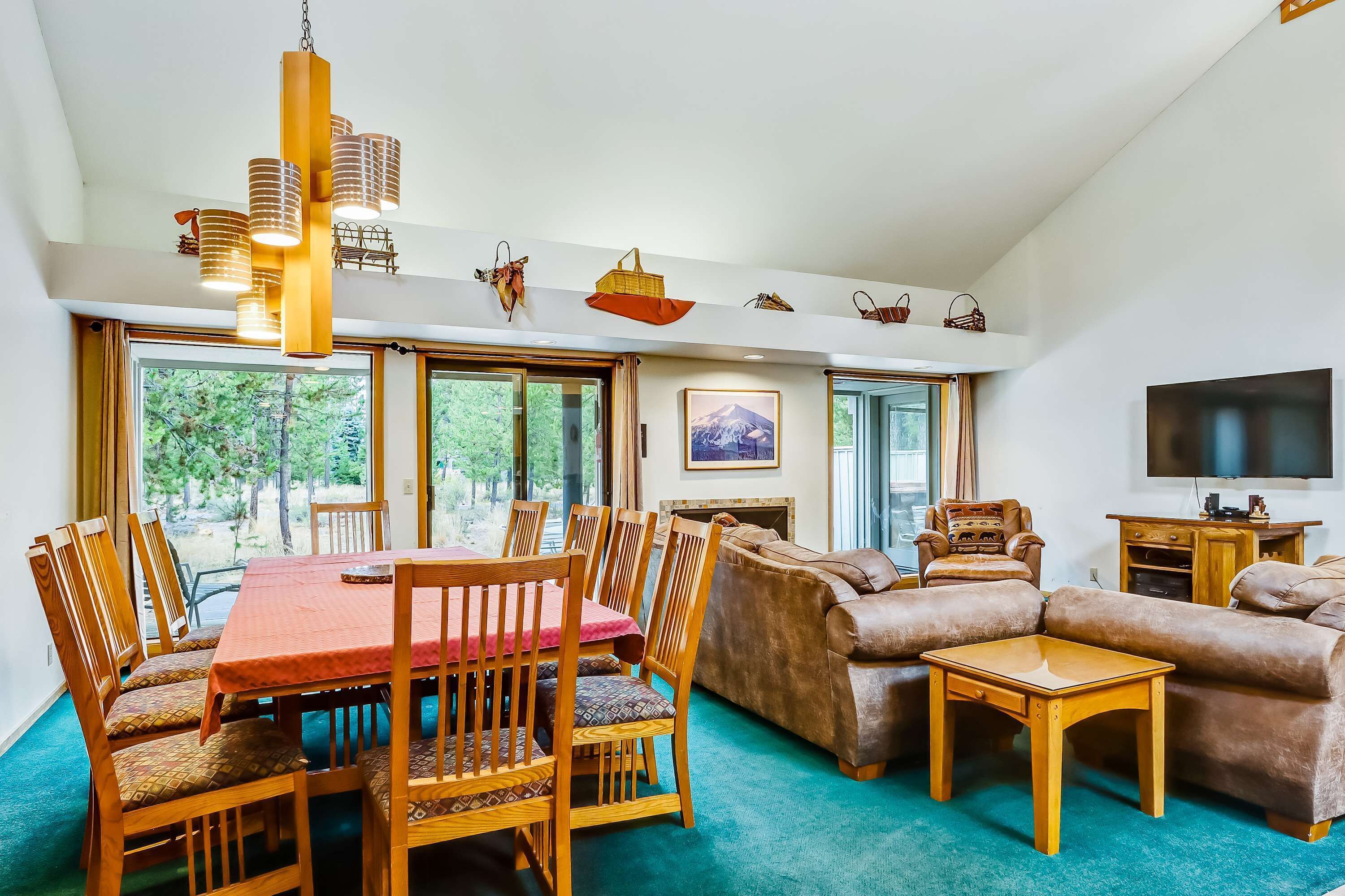 A spacious living area with a dining table, wooden chairs, a sofa, a TV, and a fireplace.