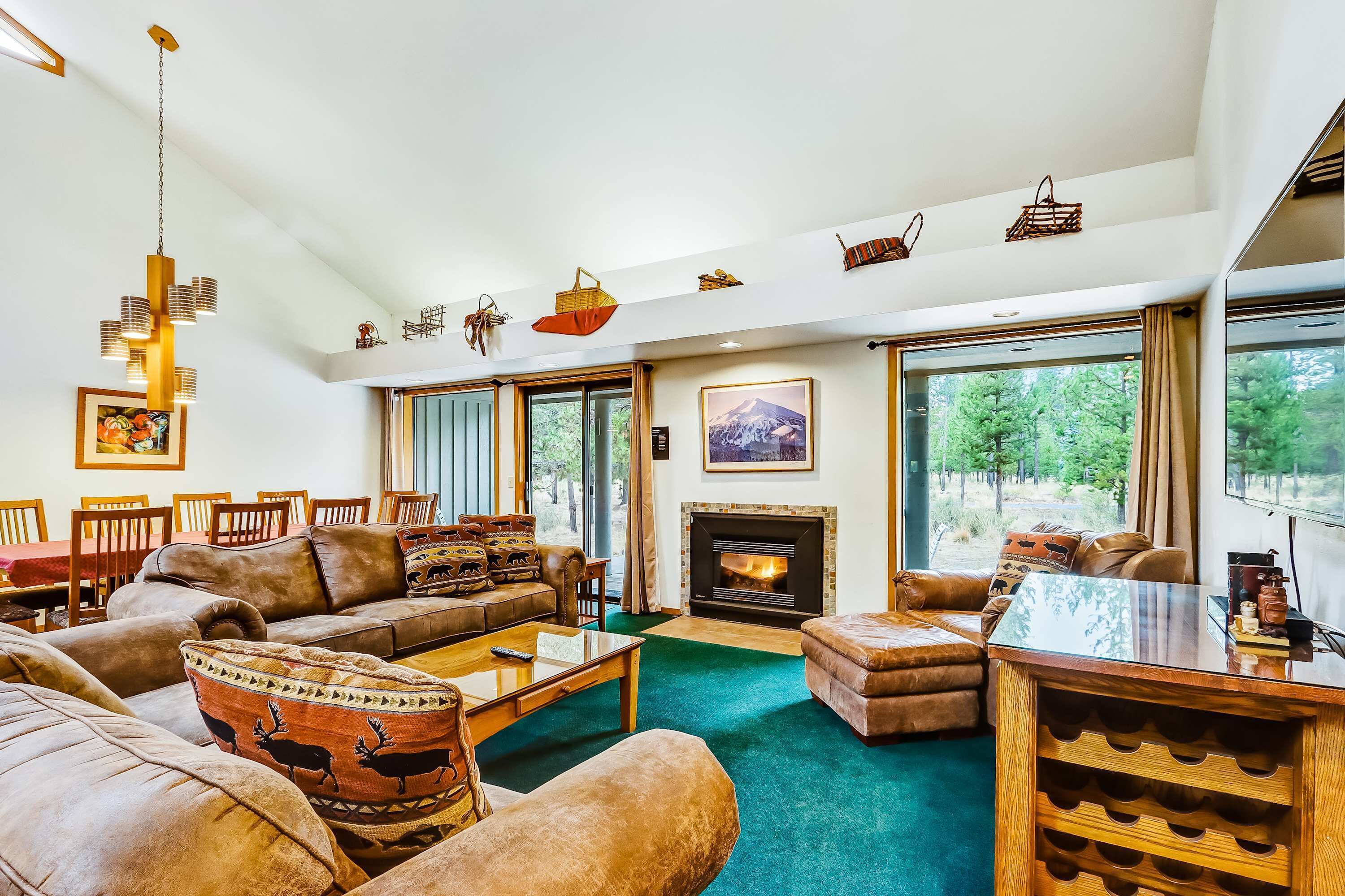 A spacious living room with a fireplace, large windows, and a dining area.
