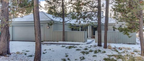 Una propiedad residencial con garaje, un espacio al aire libre cubierto y un patio cubierto de nieve.