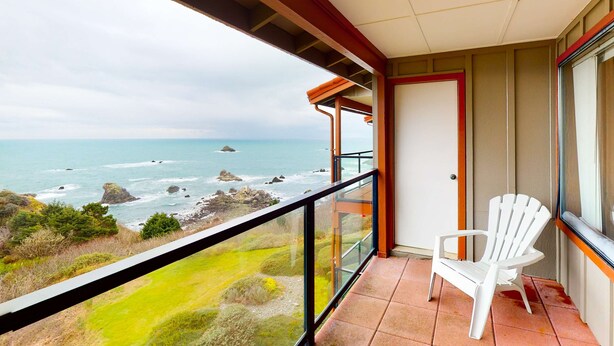 Ein Balkon mit Blick aufs Meer, ein weißer Stuhl und eine Tür.