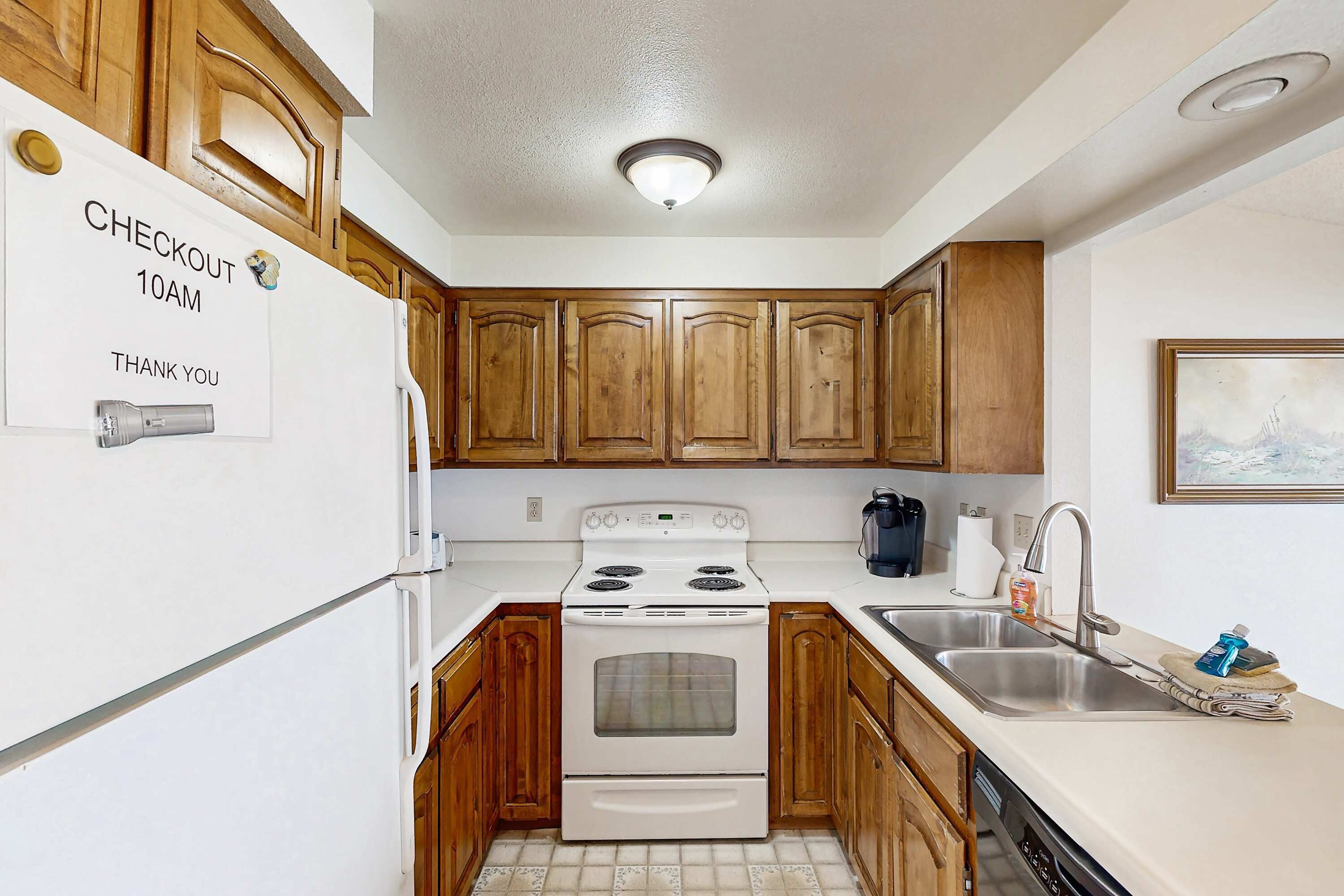 A kitchen with wooden cabinets, a white refrigerator, a stove, and a sink.