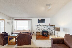A living room with a stone fireplace, a television mounted on the wall, and a sofa.