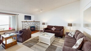 Ein Wohnzimmer mit Kamin, zwei Sofas, einem Couchtisch und einem an der Wand befestigten Fernseher.