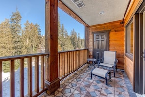 A wooden balcony with a tiled floor, a door, and two chairs. - Lovely mountain condo with shared pool, hot tub, sauna & balcony views & free WiFi (Government Camp)