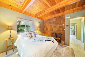 A bedroom with a wooden ceiling, a bed with nautical-themed bedding, a window with a view of greenery, and a chair. - Hidden Oasis - House in Manzanita with 3 decks, walk to the beach (Manzanita)