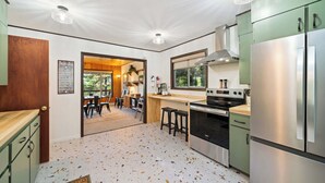 Una cucina con un piano cottura grande, un frigorifero e un'area pranzo con sedie e un tavolo.