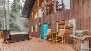 A wooden deck with a hot tub, barbecue grill, and outdoor seating. - Dog-Friendly, 3-Story Home & Loft with Deck, Private Hot Tub, Gas Grill, Pool Table (Government Camp)