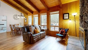 Een houten interieur met een leren bank, een eettafel, stoelen en een open haard.