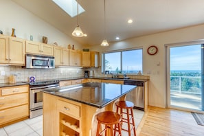 A kitchen with wooden cabinets, a stainless steel oven, a microwave, and a large island with stools.