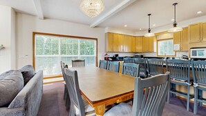 A dining area with a wooden table and chairs, a chandelier, and wooden cabinets. - Large home 1 block from the beach with ocean view, game room, fireplace & WiFi (Seaside)