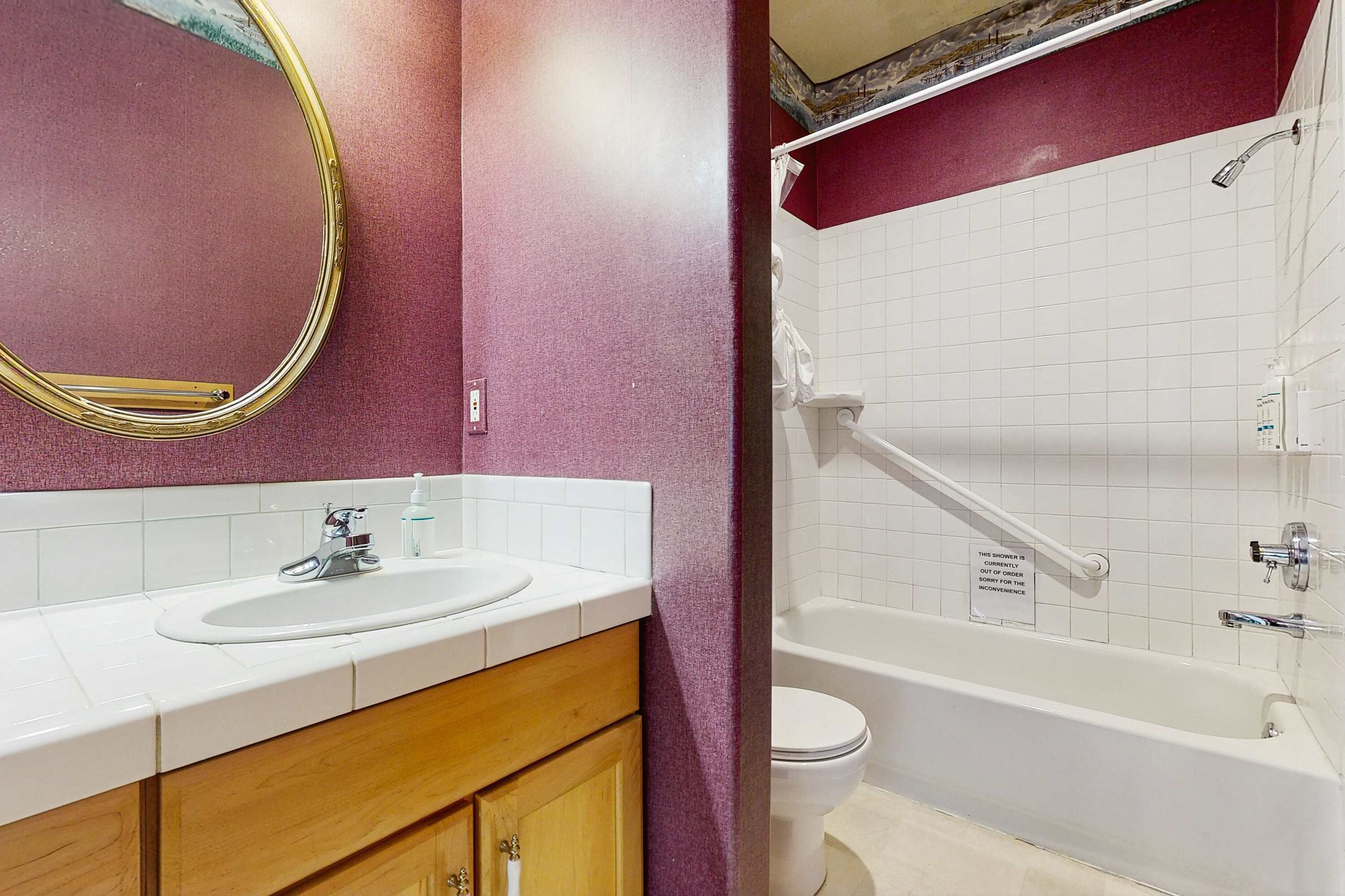 A bathroom with a white sink, mirror, and bathtub.